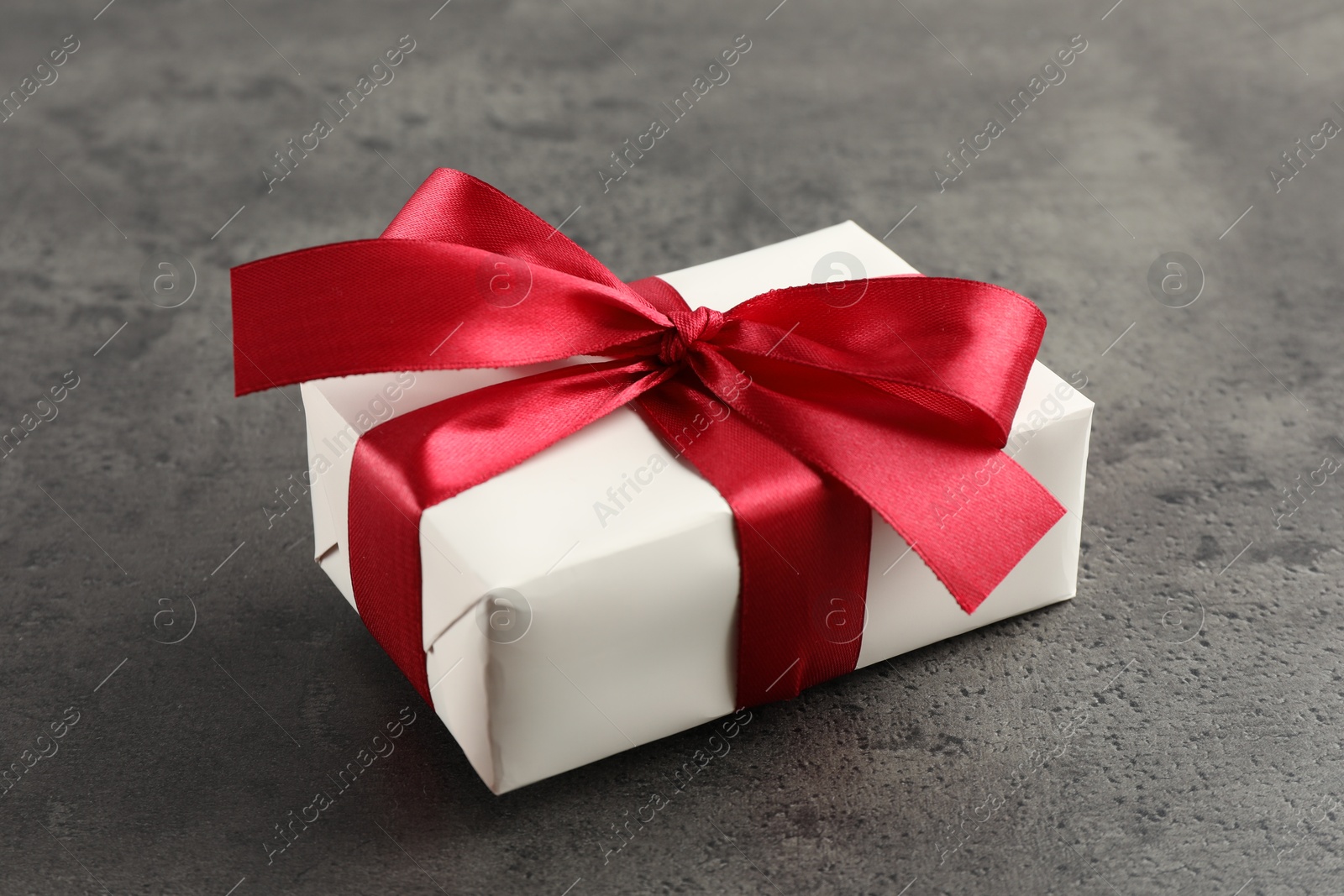 Photo of Gift box with bow on grey table