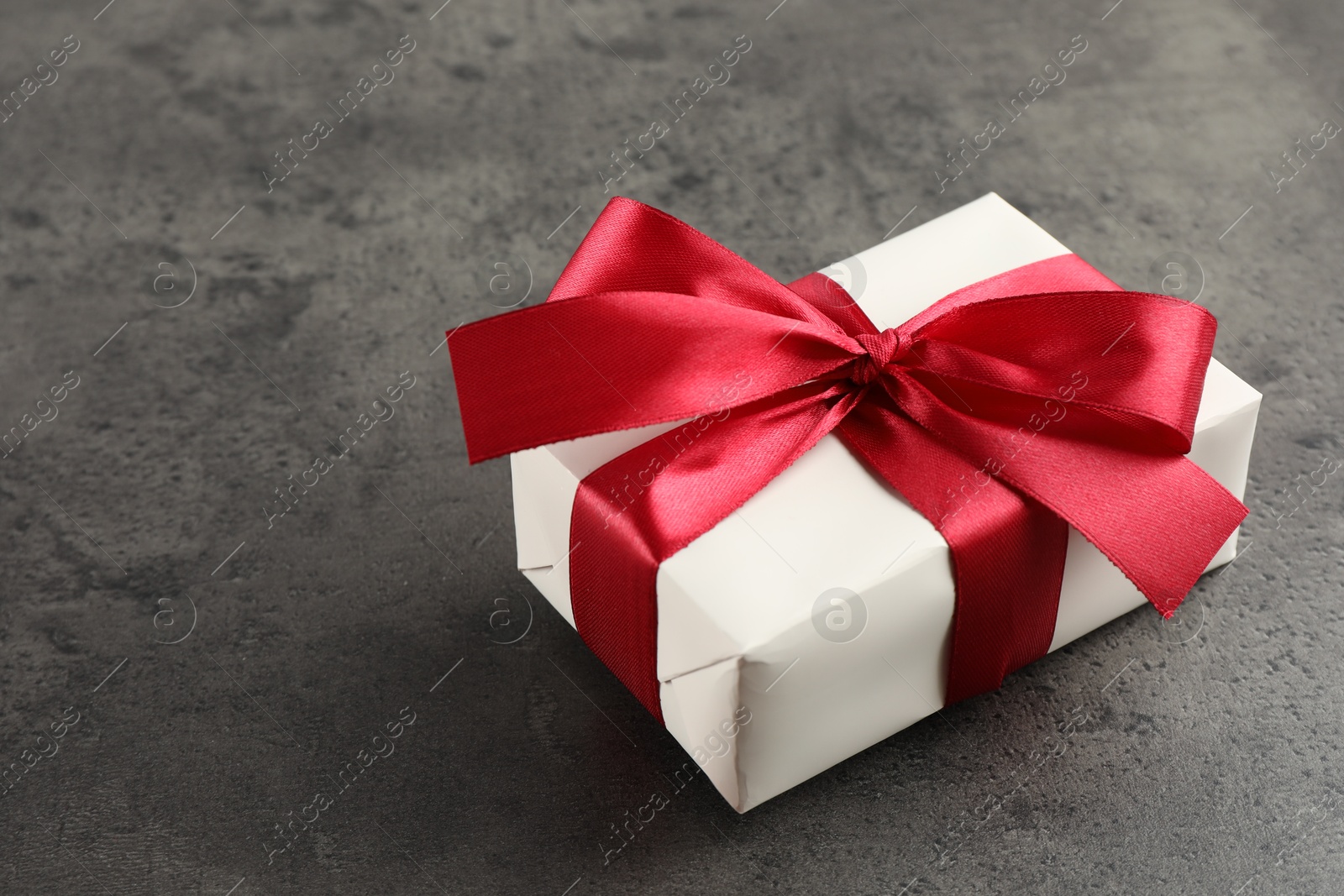 Photo of Gift box with bow on grey table, space for text