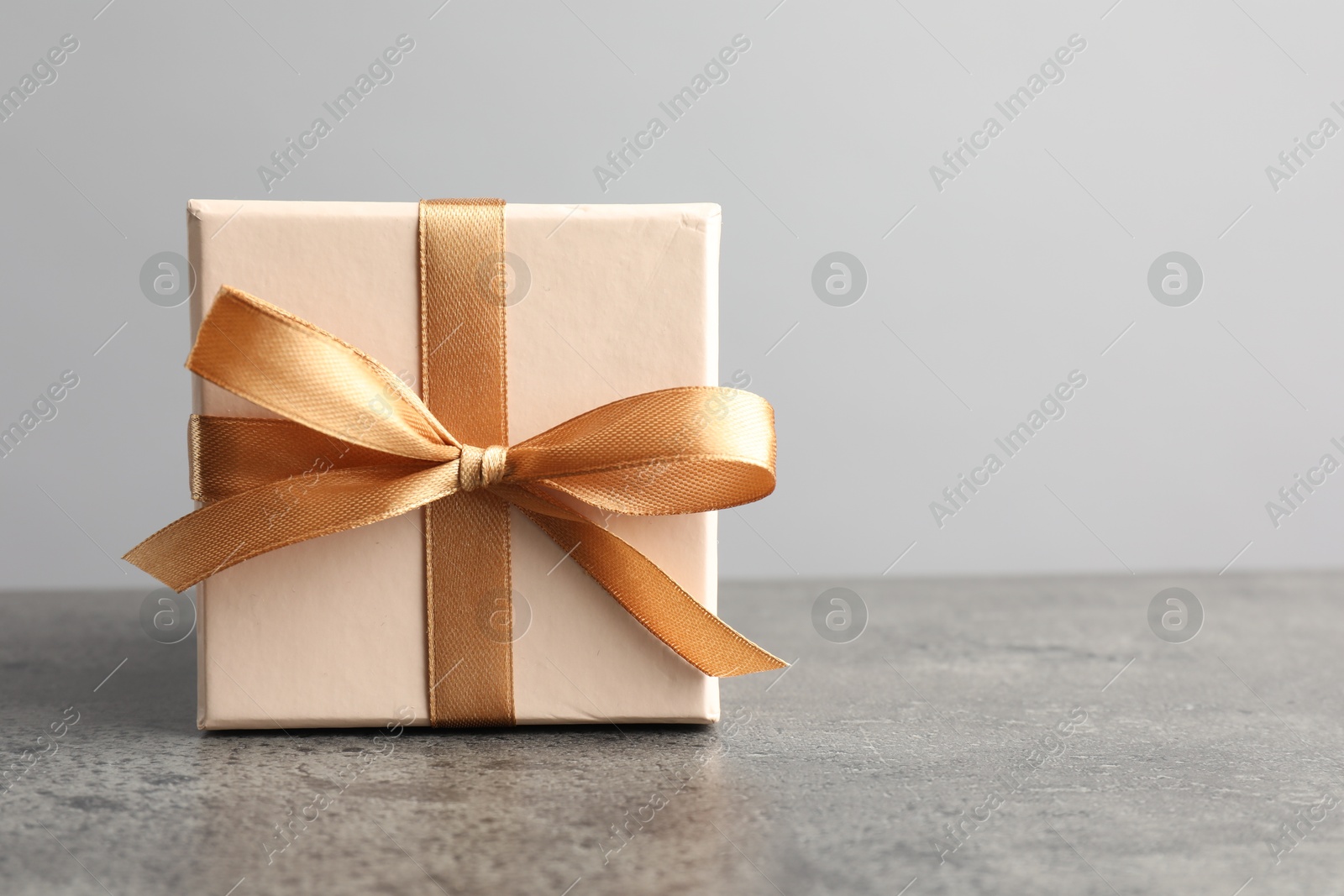 Photo of Gift box with bow on grey table, space for text