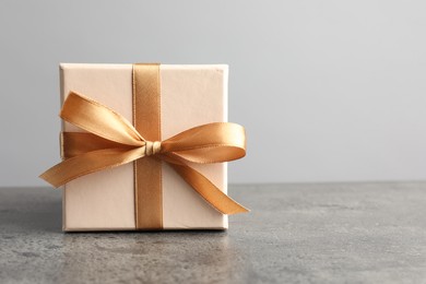 Photo of Gift box with bow on grey table, space for text