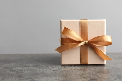 Photo of Gift box with bow on grey table, space for text