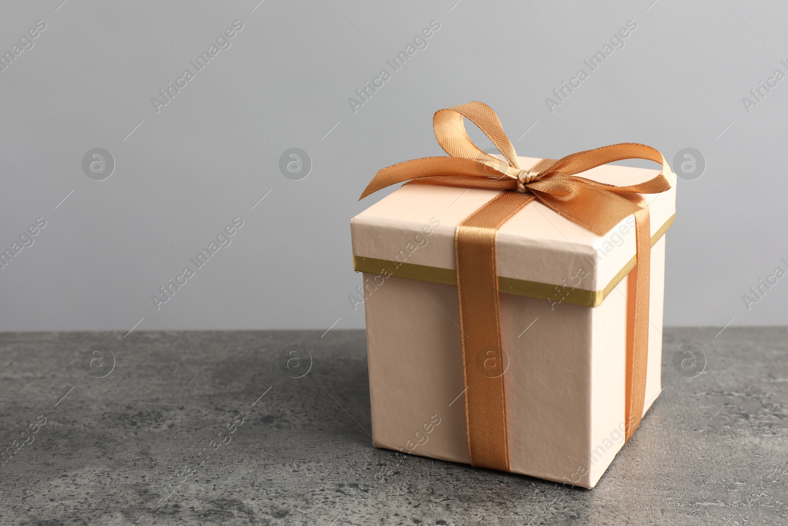 Photo of Gift box with bow on grey table, space for text