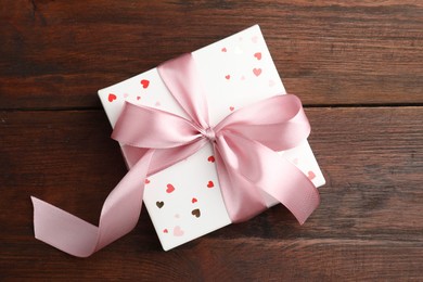 Gift box with bow on wooden table, top view