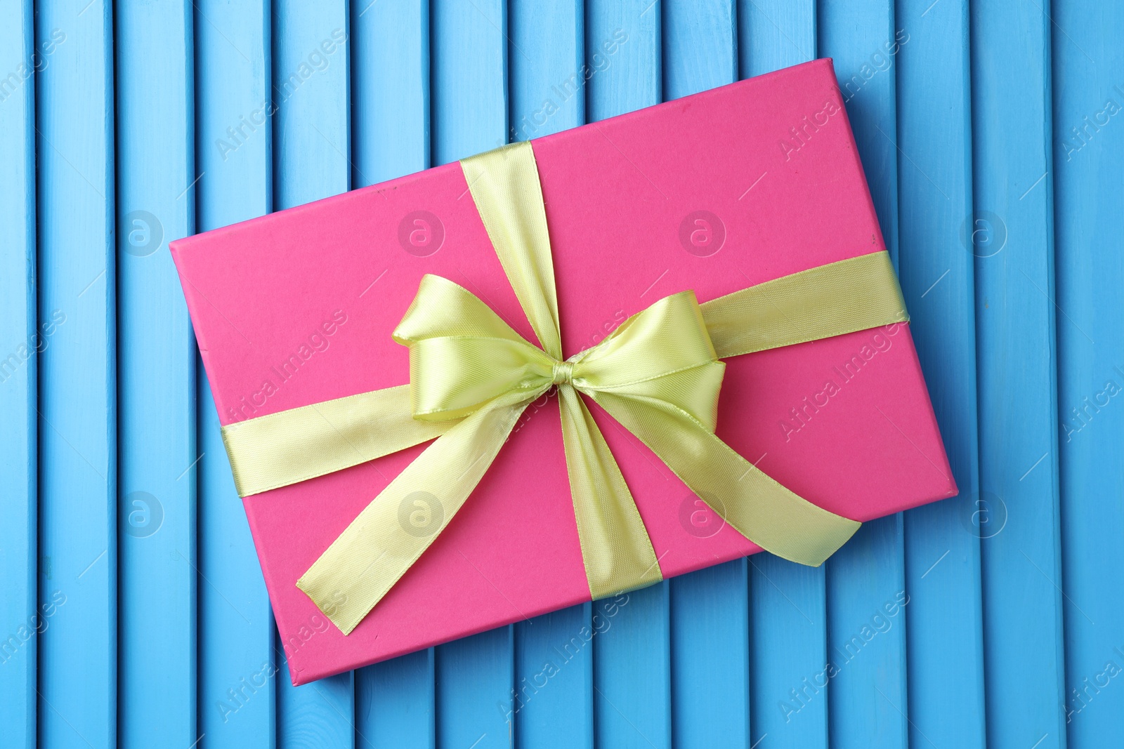 Photo of Gift box with bow on blue textured table, top view