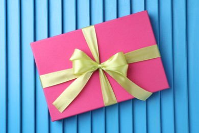 Photo of Gift box with bow on blue textured table, top view