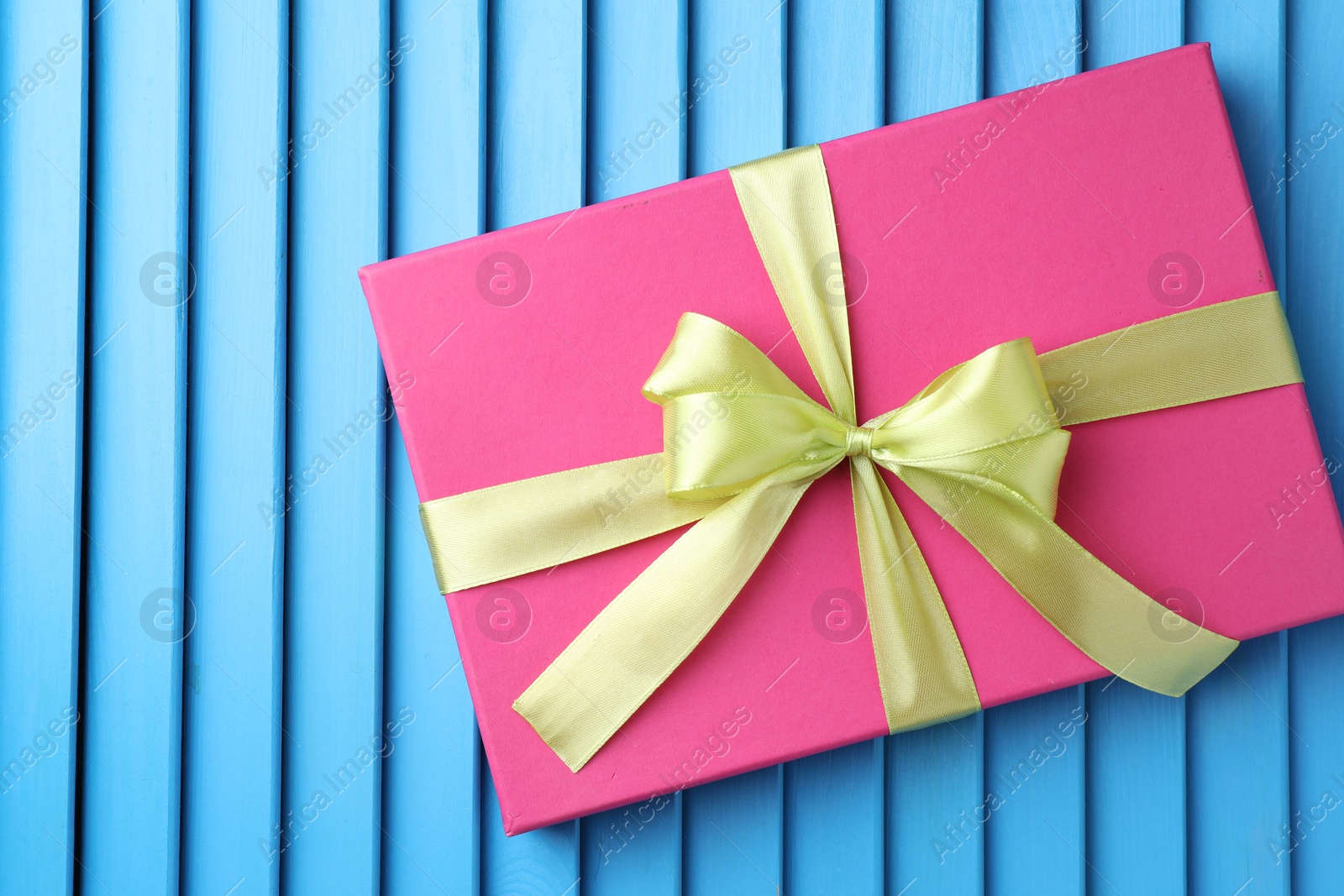 Photo of Gift box with bow on blue textured table, top view