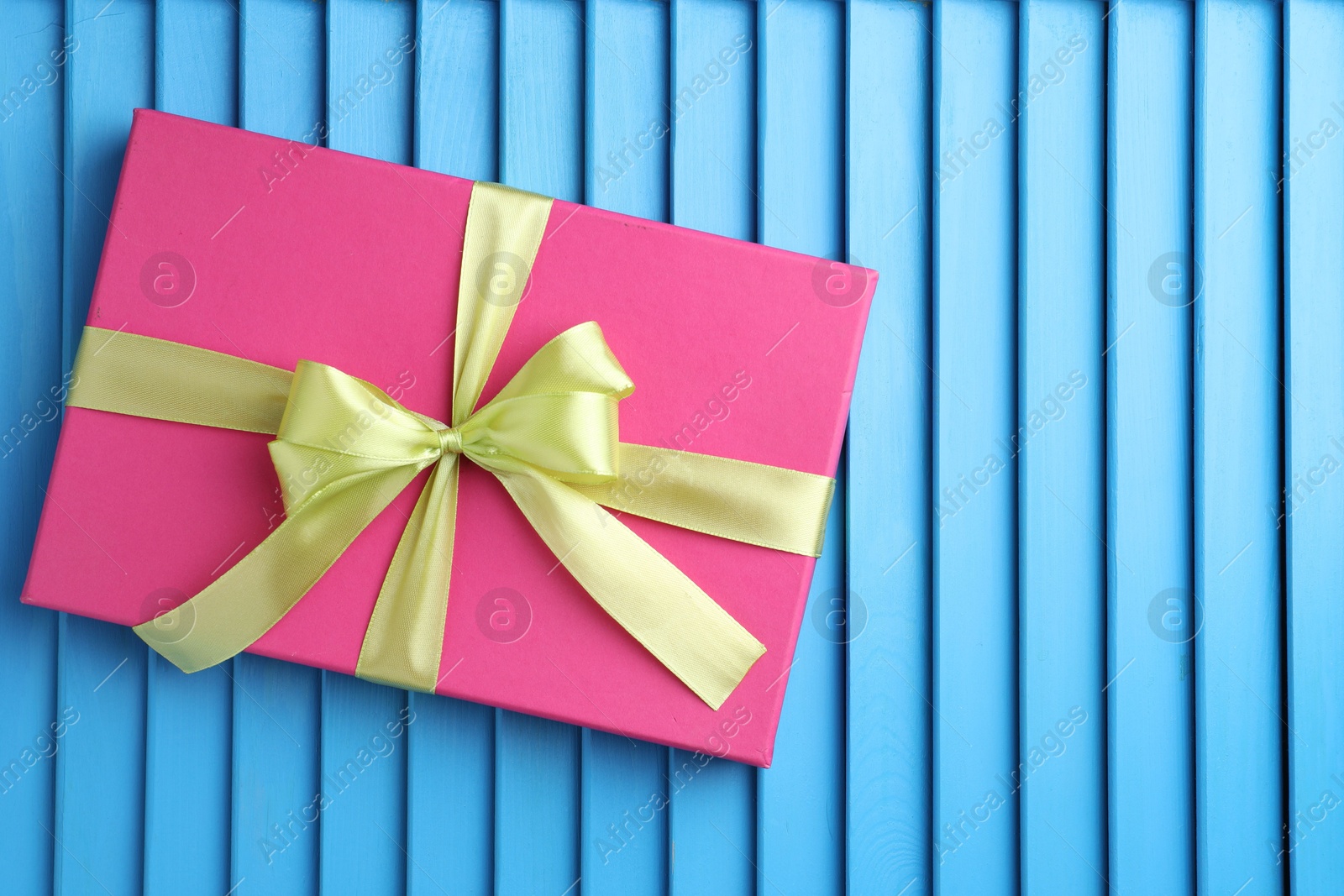 Photo of Gift box with bow on blue textured table, top view. Space for text