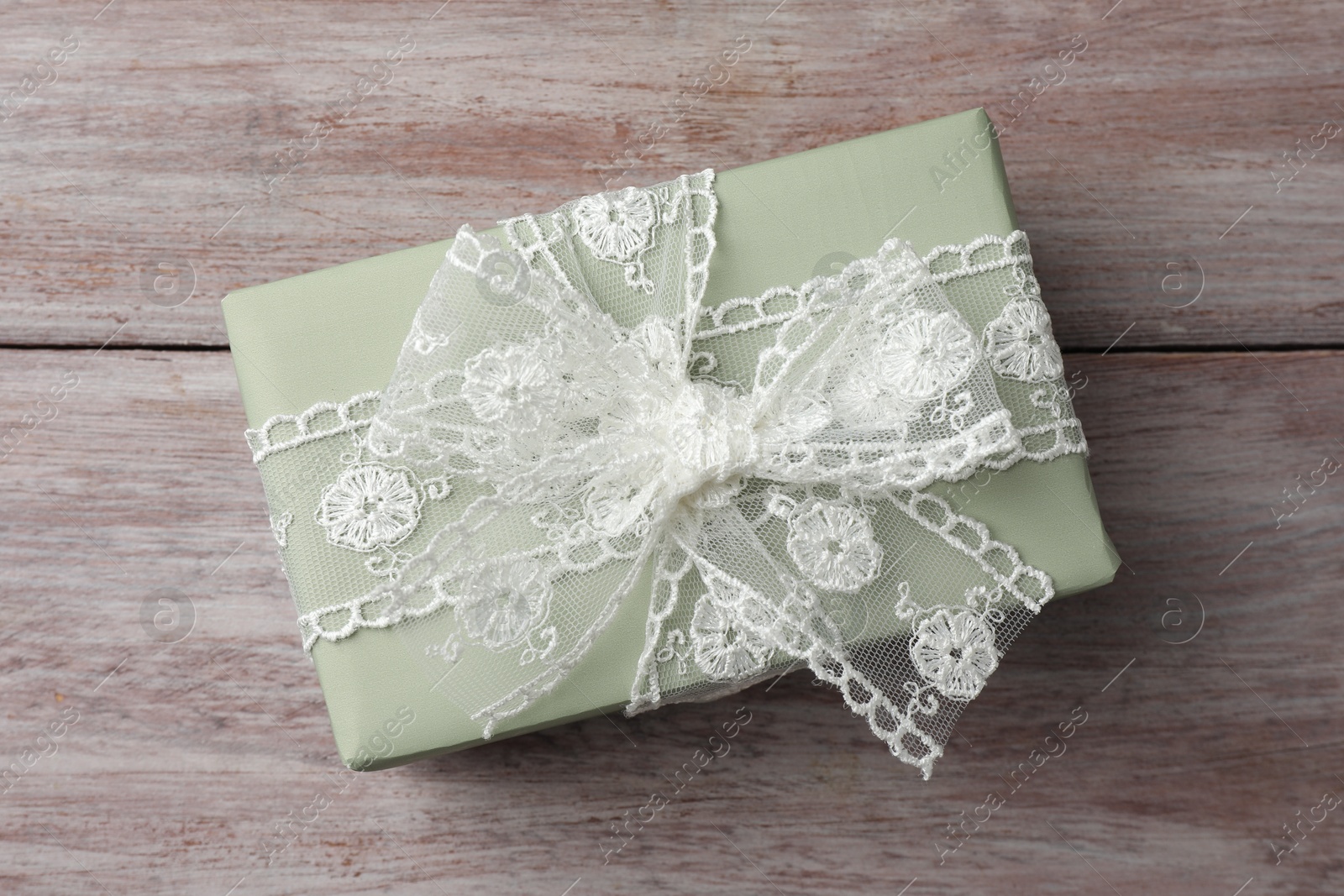 Photo of Gift box with bow on pink wooden table, top view