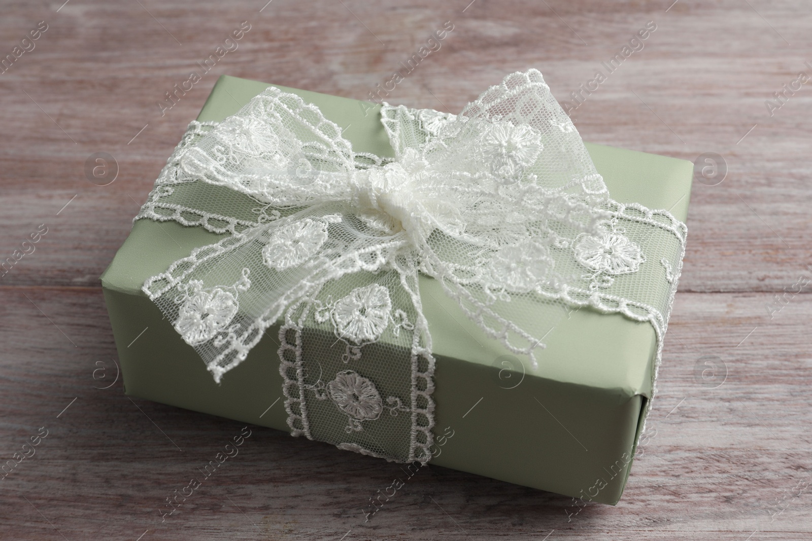 Photo of Gift box with bow on pink wooden table