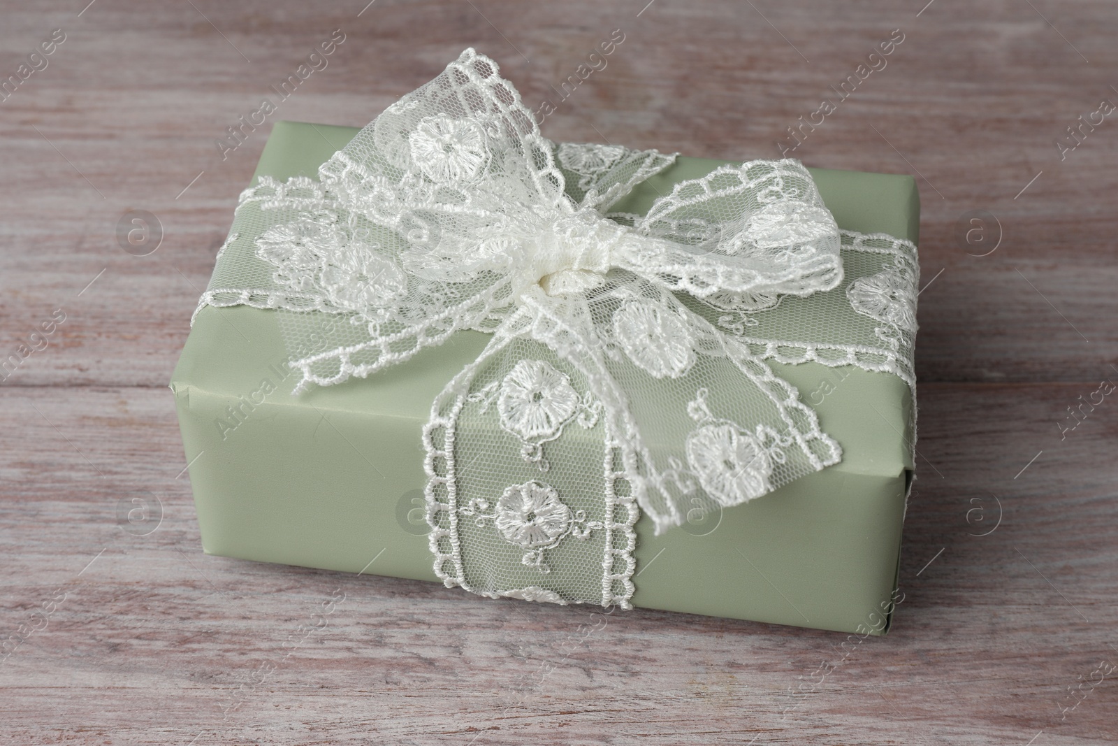 Photo of Gift box with bow on pink wooden table