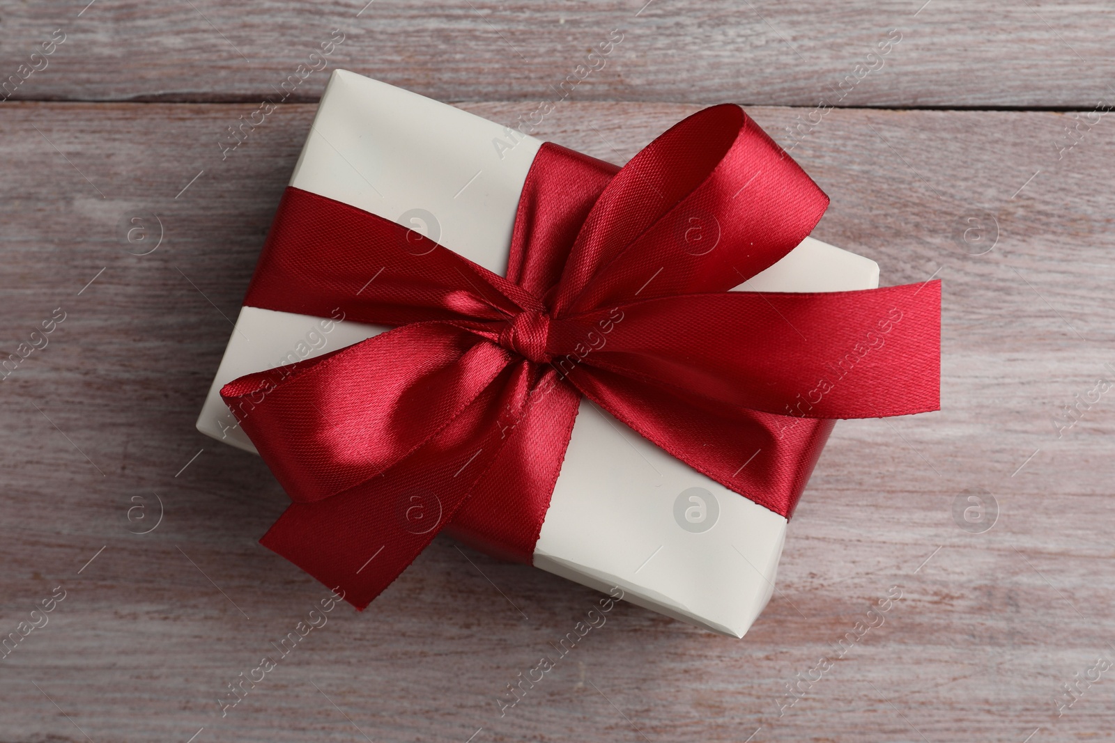 Photo of Gift box with bow on pink wooden table, top view