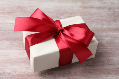 Photo of Gift box with bow on pink wooden table