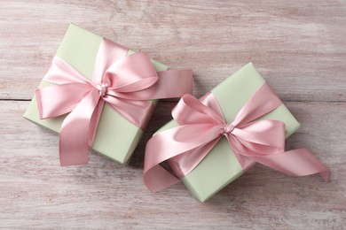 Photo of Gift boxes with bows on pink wooden table, flat lay