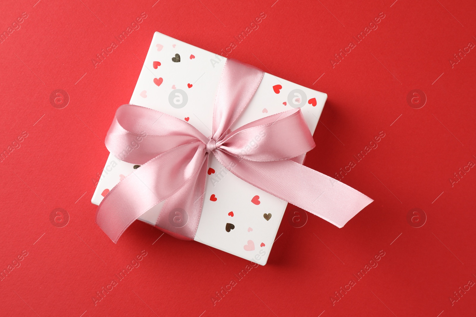 Photo of Gift box with bow on red background, top view