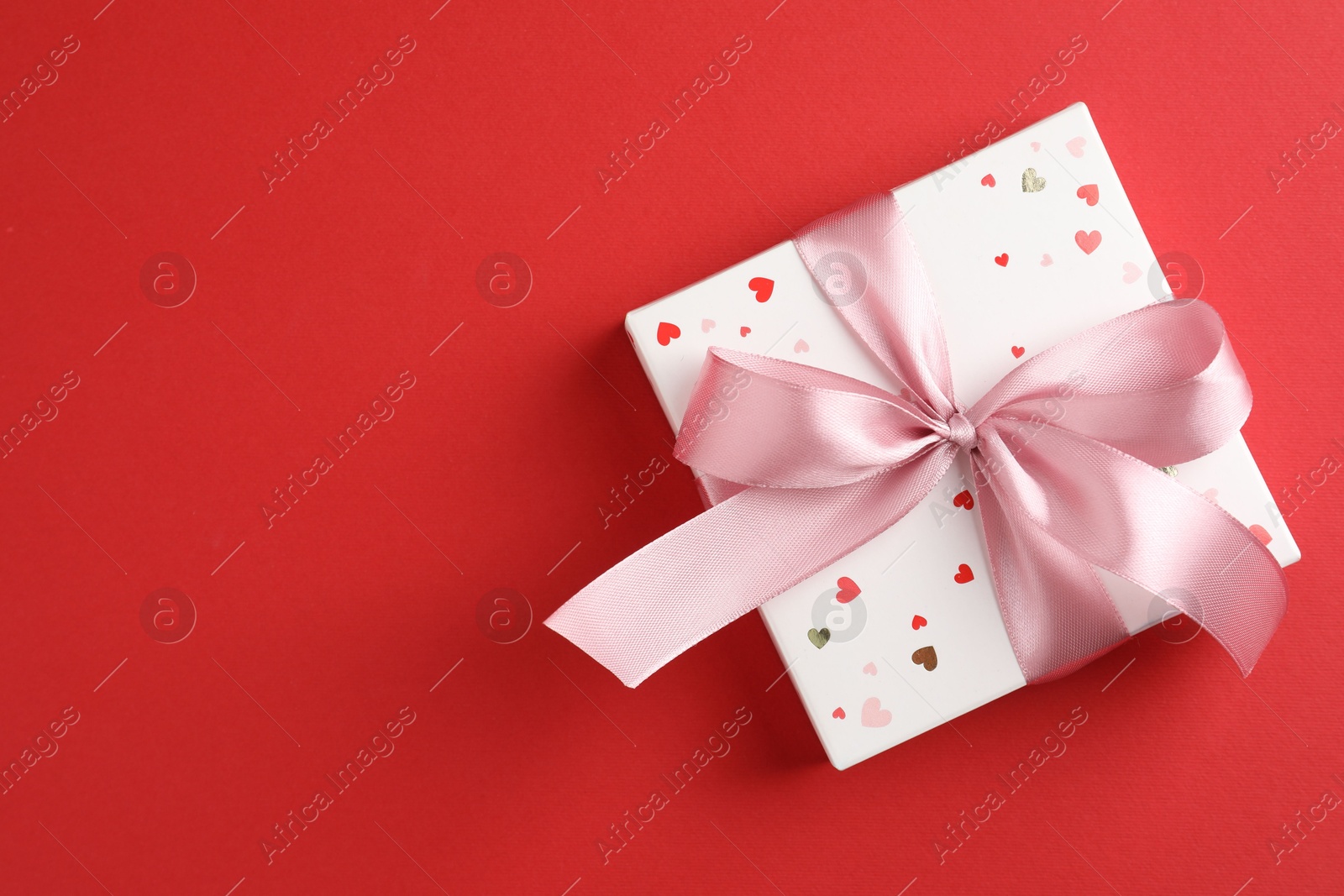 Photo of Gift box with bow on red background, top view. Space for text