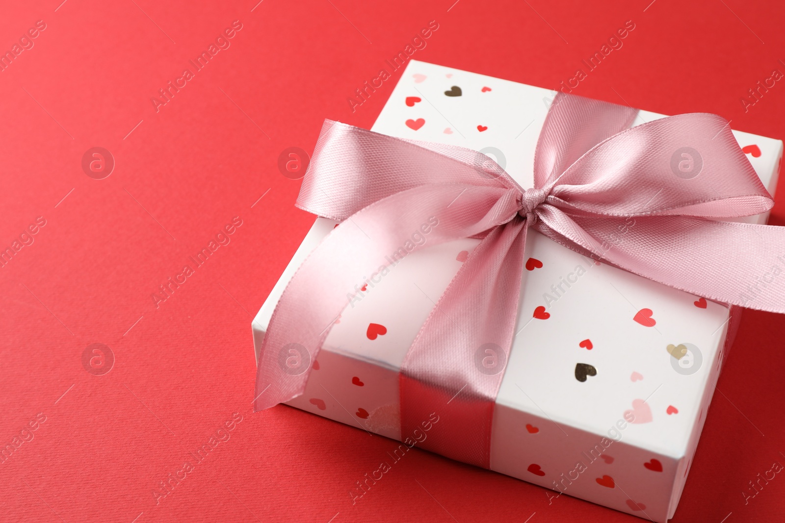 Photo of Gift box with bow on red background, closeup. Space for text