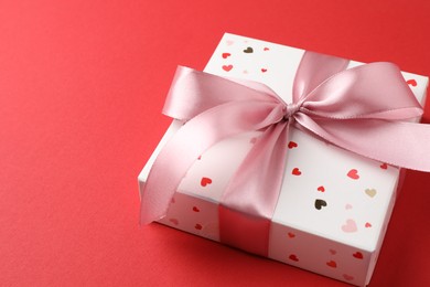 Photo of Gift box with bow on red background, closeup. Space for text