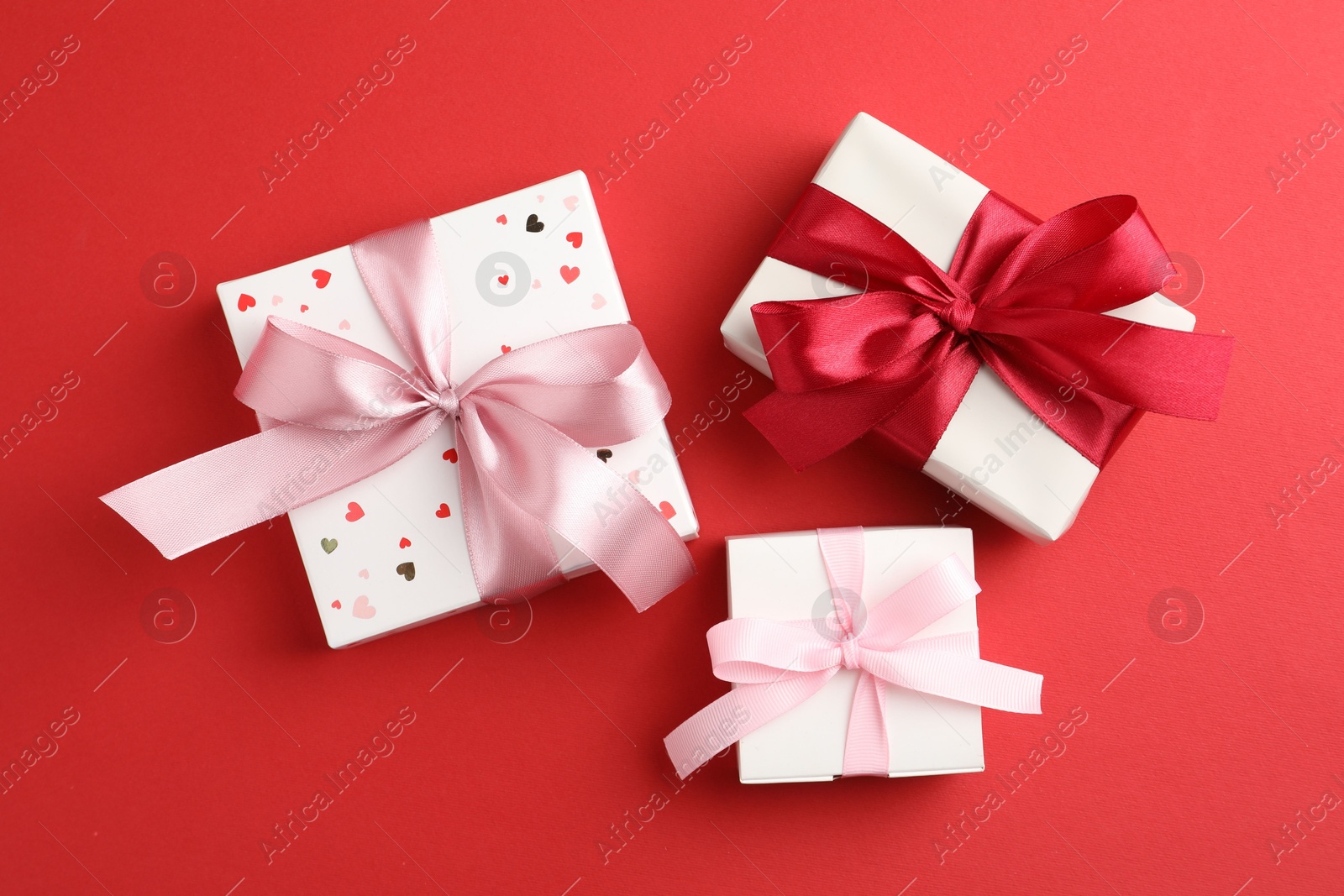 Photo of Gift boxes with bows on red background, flat lay