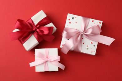 Photo of Gift boxes with bows on red background, flat lay