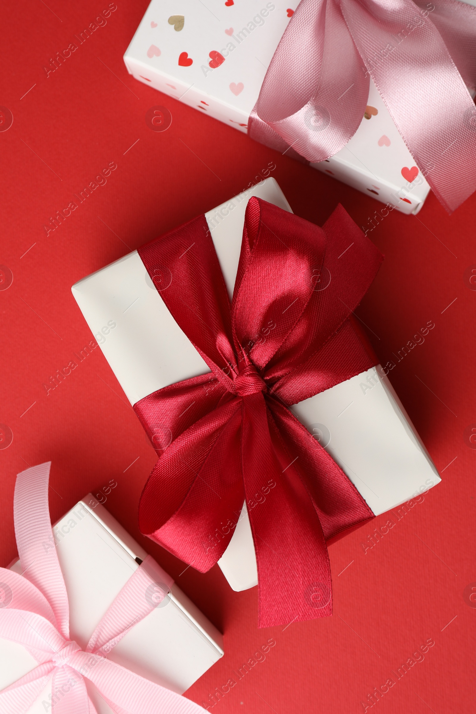 Photo of Gift boxes with bows on red background, flat lay