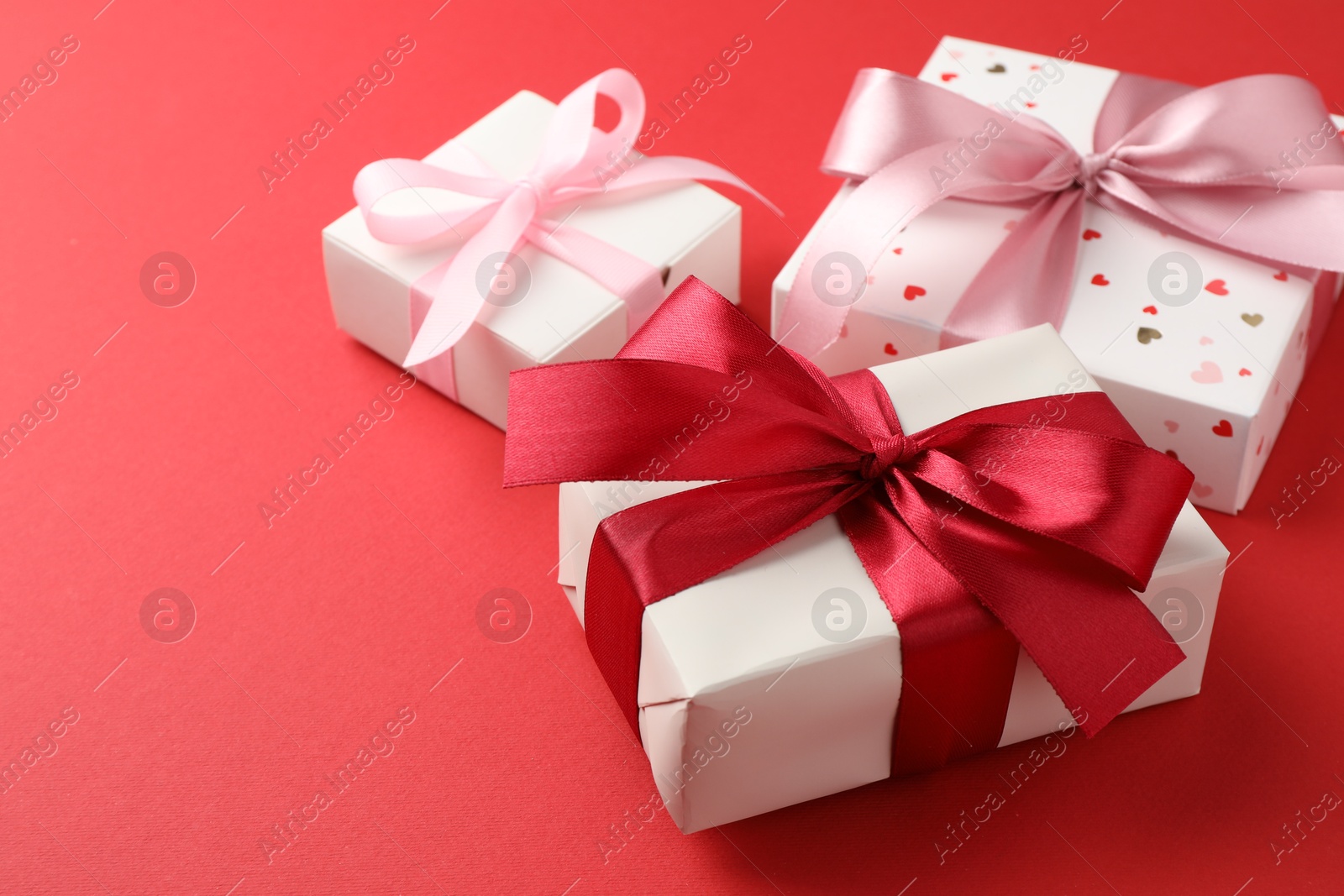 Photo of Gift boxes with bows on red background, space for text