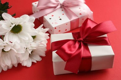 Photo of Gift boxes with bows and flowers on red background