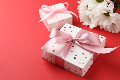 Photo of Gift boxes with bows and flowers on red background