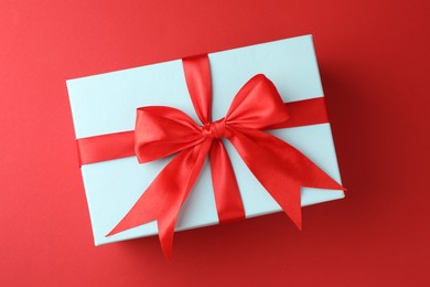 Photo of Gift box with bow on red background, top view