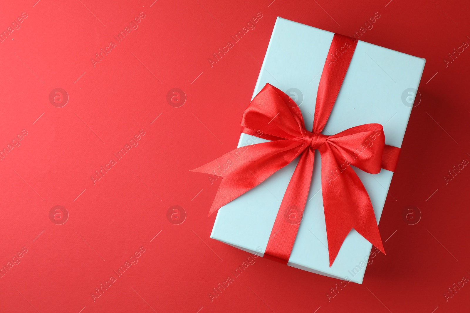 Photo of Gift box with bow on red background, top view. Space for text