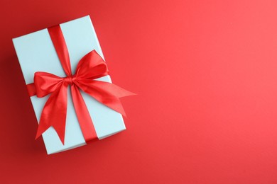 Photo of Gift box with bow on red background, top view. Space for text