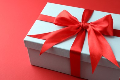 Photo of Gift box with bow on red background, closeup