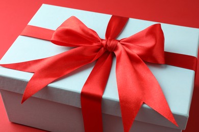 Gift box with bow on red background, closeup