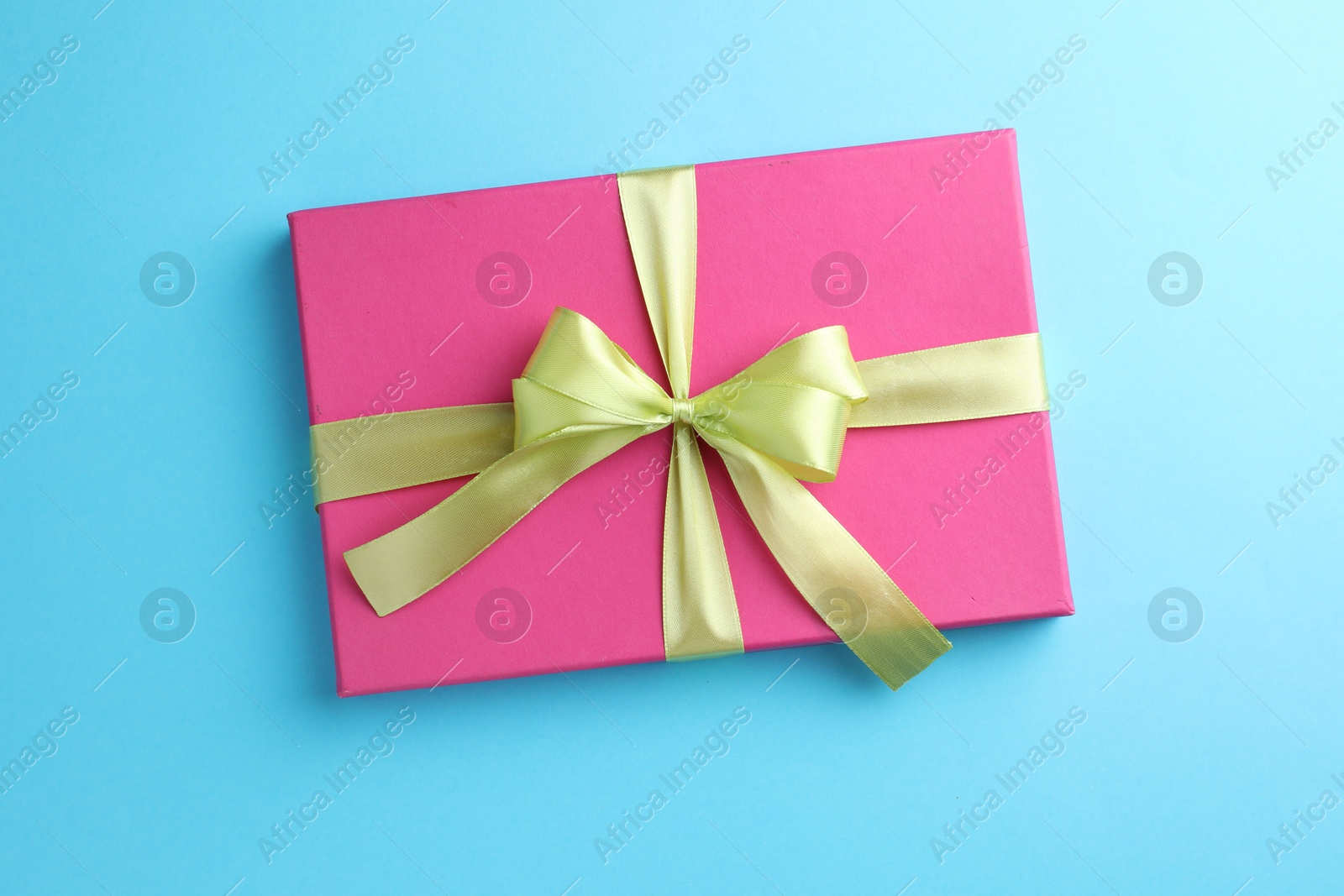 Photo of Gift box with bow on light blue background, top view