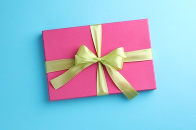 Photo of Gift box with bow on light blue background, top view