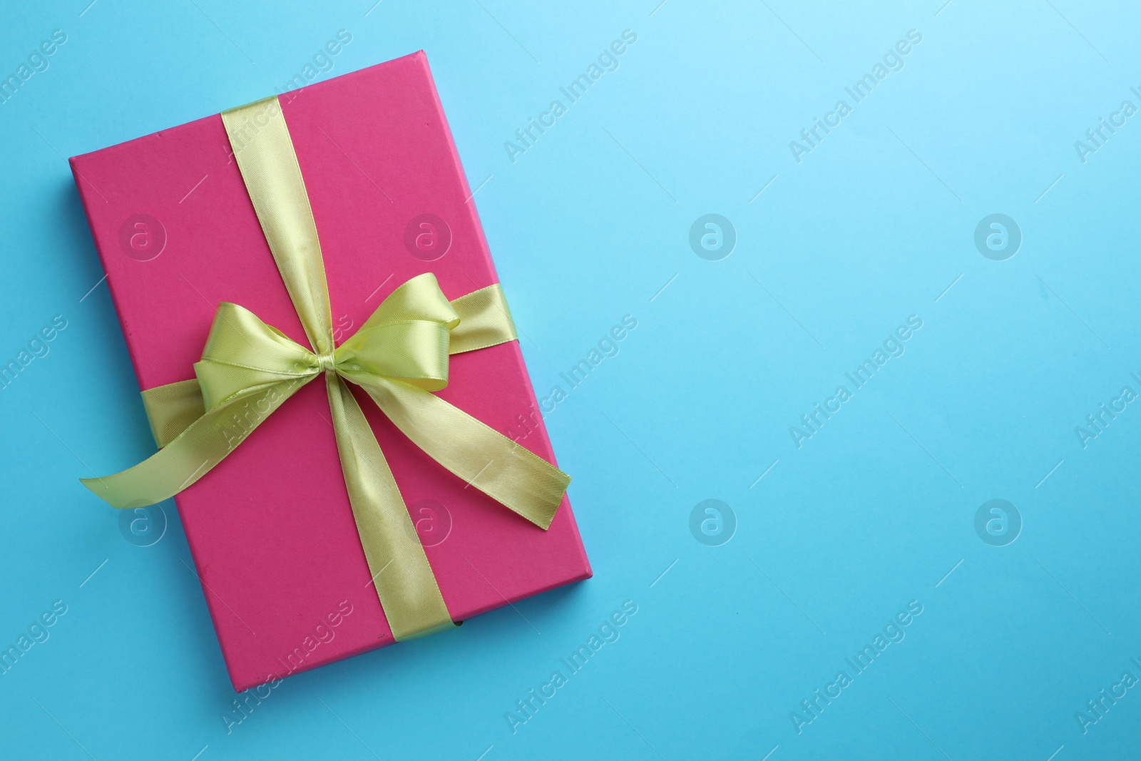 Photo of Gift box with bow on light blue background, top view. Space for text