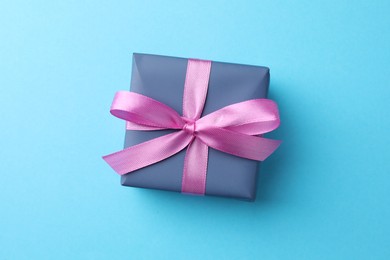 Photo of Gift box with bow on light blue background, top view