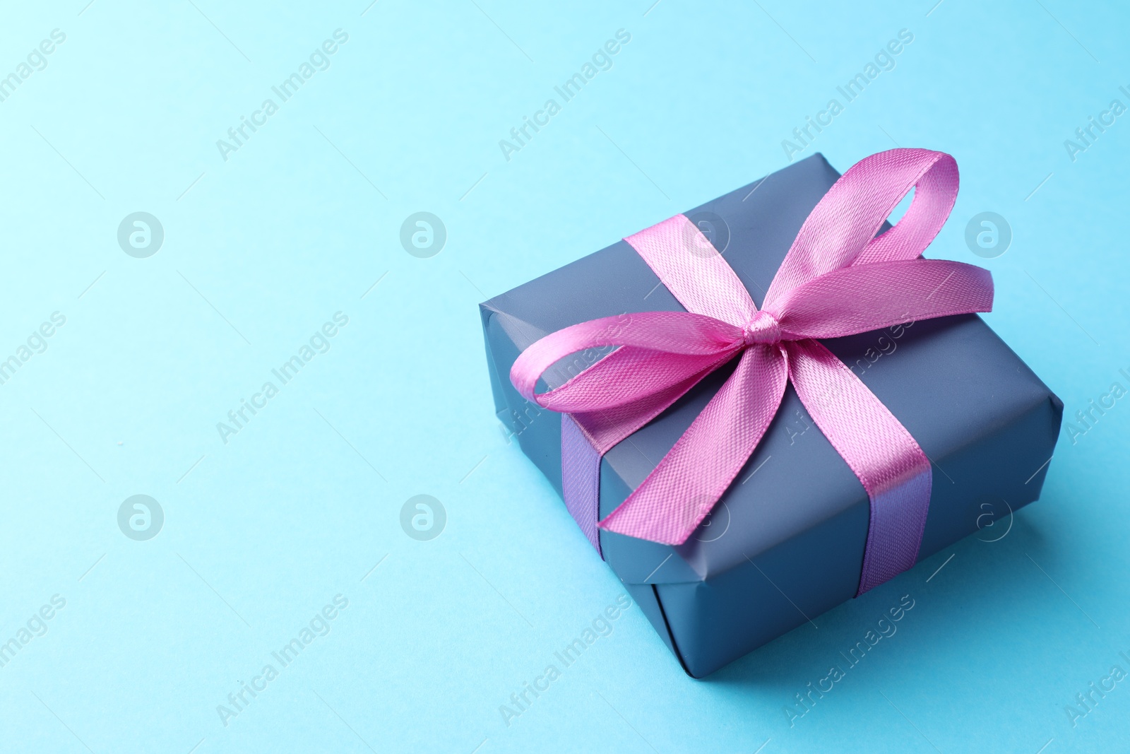 Photo of Gift box with bow on light blue background, space for text