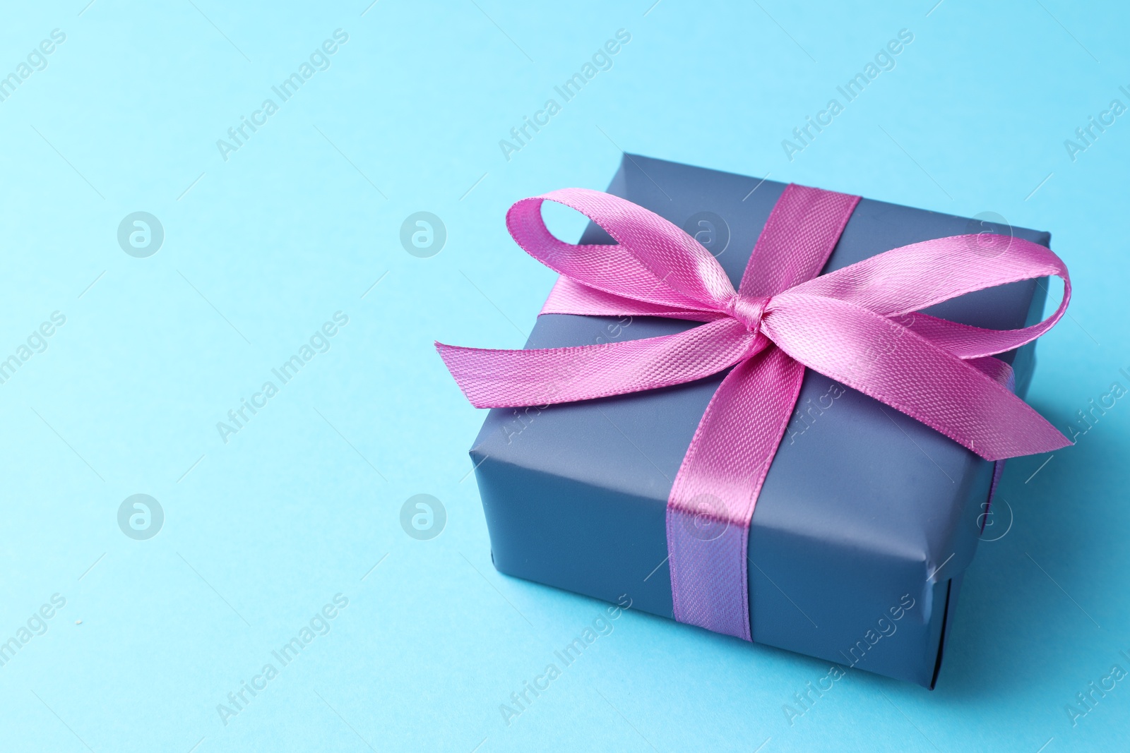 Photo of Gift box with bow on light blue background, space for text