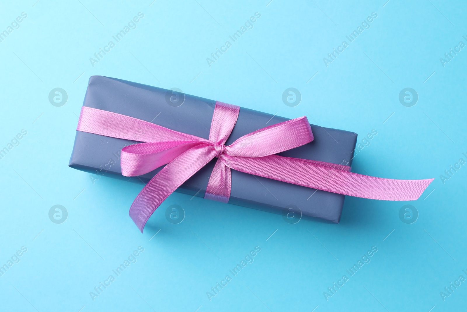 Photo of Gift box with bow on light blue background, top view