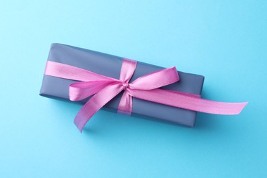 Photo of Gift box with bow on light blue background, top view