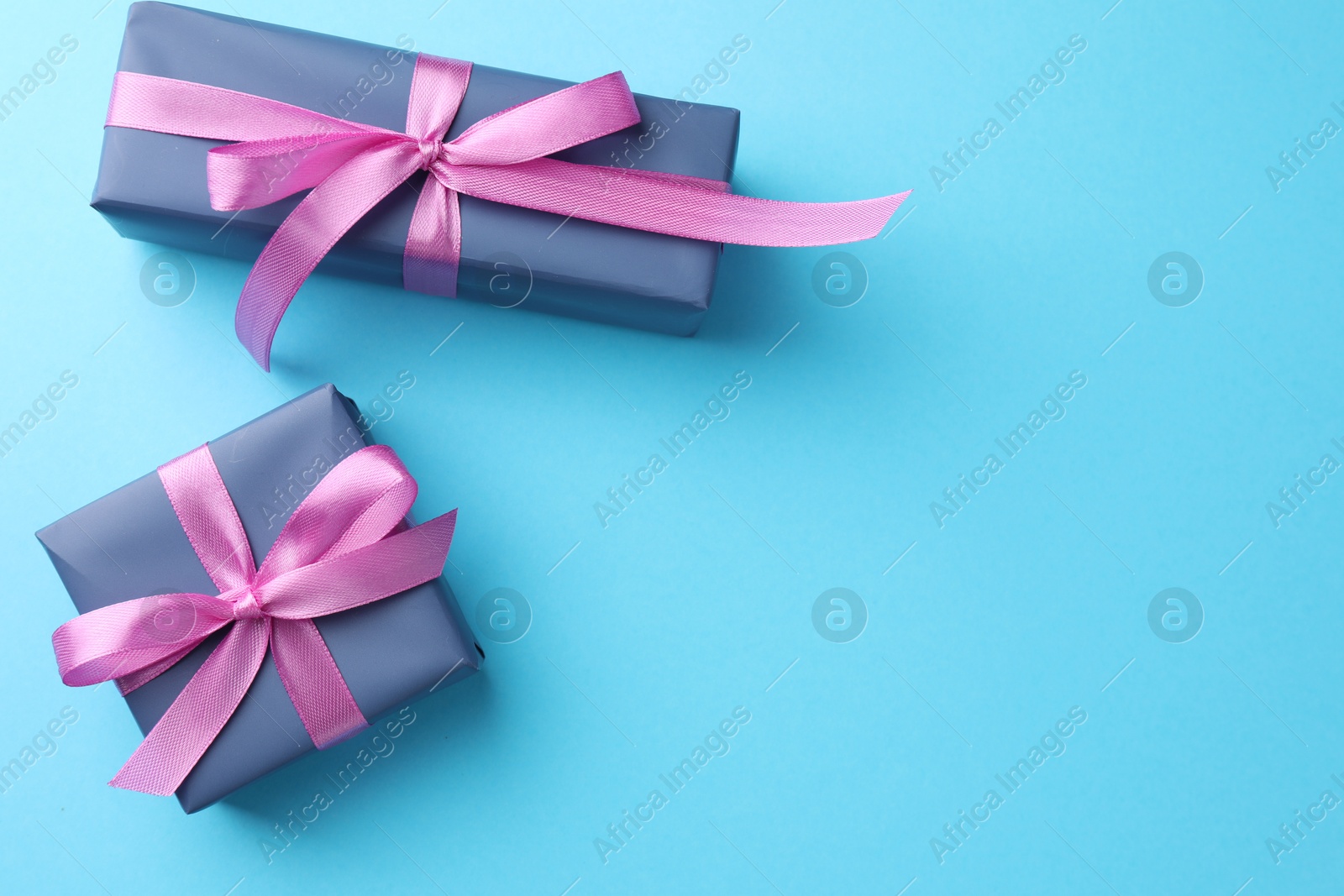 Photo of Gift boxes with bows on light blue background, flat lay. Space for text