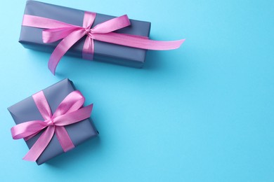 Photo of Gift boxes with bows on light blue background, flat lay. Space for text