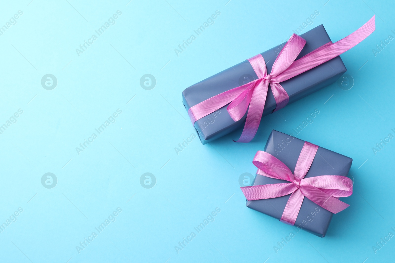 Photo of Gift boxes with bows on light blue background, flat lay. Space for text