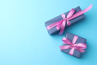 Photo of Gift boxes with bows on light blue background, flat lay. Space for text