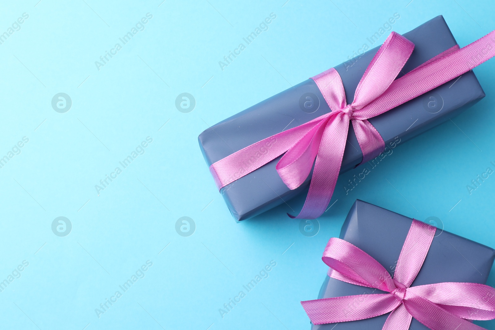 Photo of Gift boxes with bows on light blue background, flat lay. Space for text