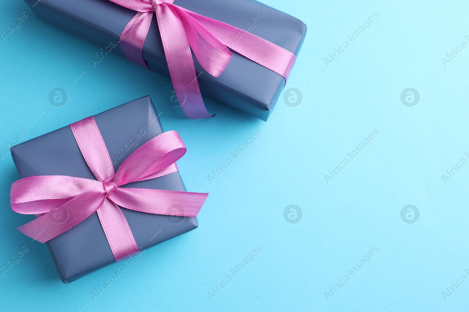 Photo of Gift boxes with bows on light blue background, flat lay. Space for text