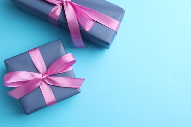 Photo of Gift boxes with bows on light blue background, flat lay. Space for text