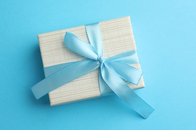 Photo of Gift box with bow on light blue background, top view