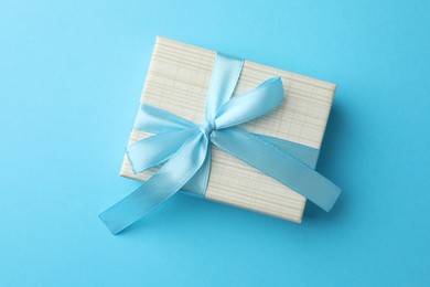 Photo of Gift box with bow on light blue background, top view