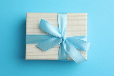 Photo of Gift box with bow on light blue background, top view